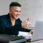 pexels photo 6325981 6325981 Happy man gives thumbs up while video conferencing from home office.